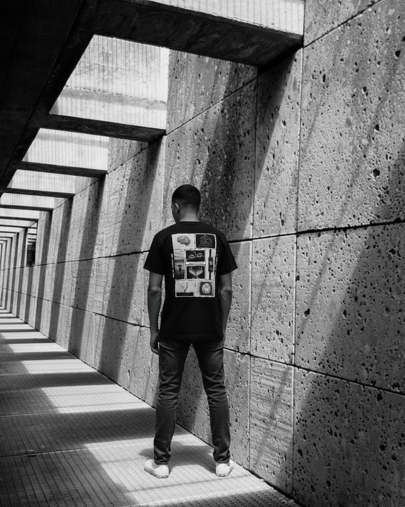 Person standing in a sunlit concrete corridor with geometric patterns.